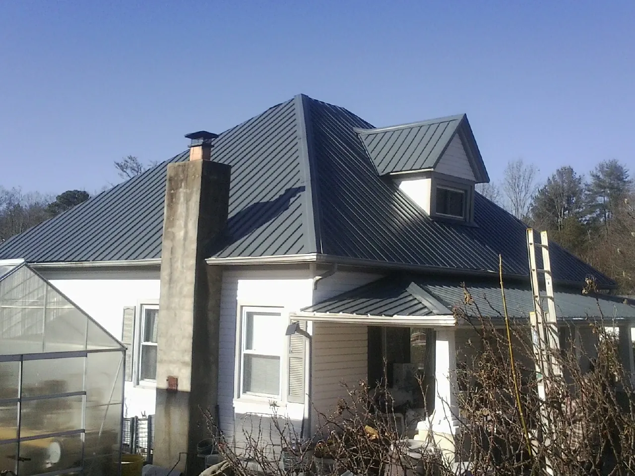 Dark blue standing seam metal roof on a white farmhouse with dormer — Slate & Tile Roof Repair by Roofing Brothers in Mattawan