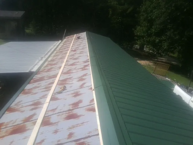 Old rusted panels beside newly installed green metal roofing — Wind Damage Roof Repair by Roofing Brothers in Mattawan
