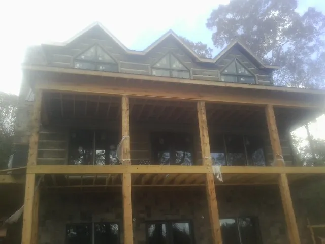Dormers and porch framing on a large log home under construction — Roof Coating work by our crew in Mattawan