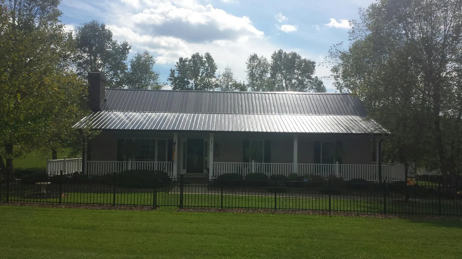 Gray metal roof on a brick ranch with a full width front porch — Gutter Guard Installation work by our crew in Mattawan