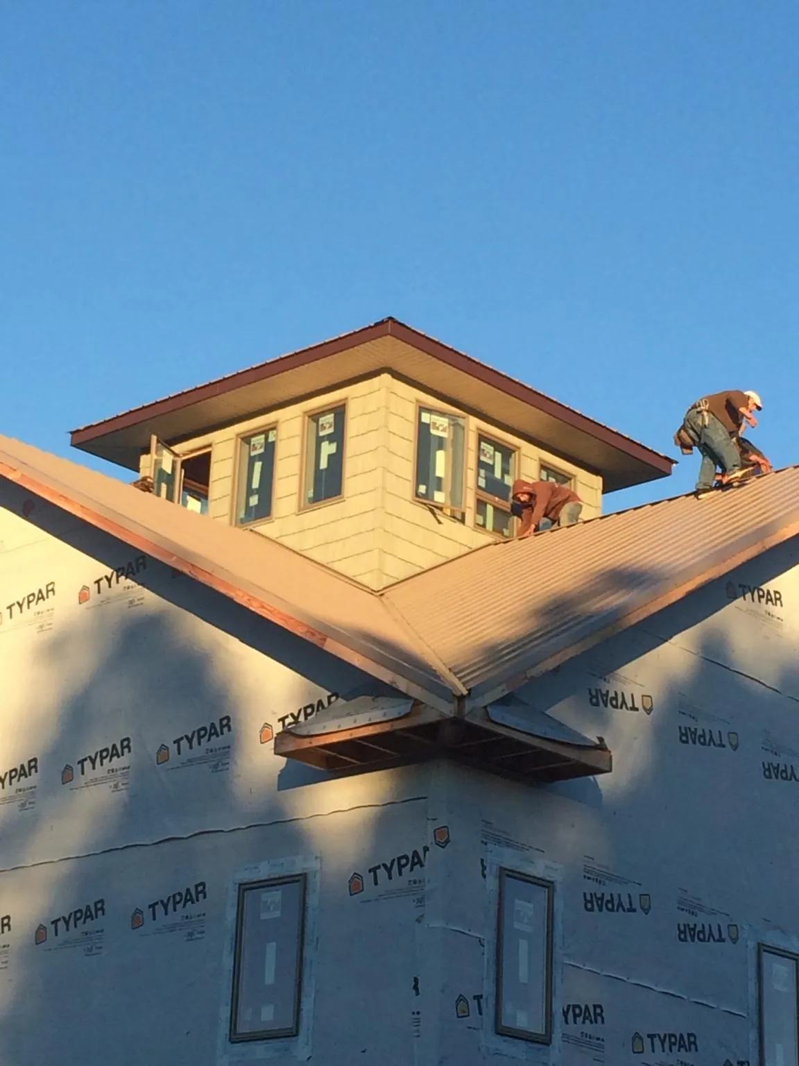 Roofers working around a rooftop cupola on a new metal roof at sunset — Roof Waterproofing in Mattawan by Roofing Brothers